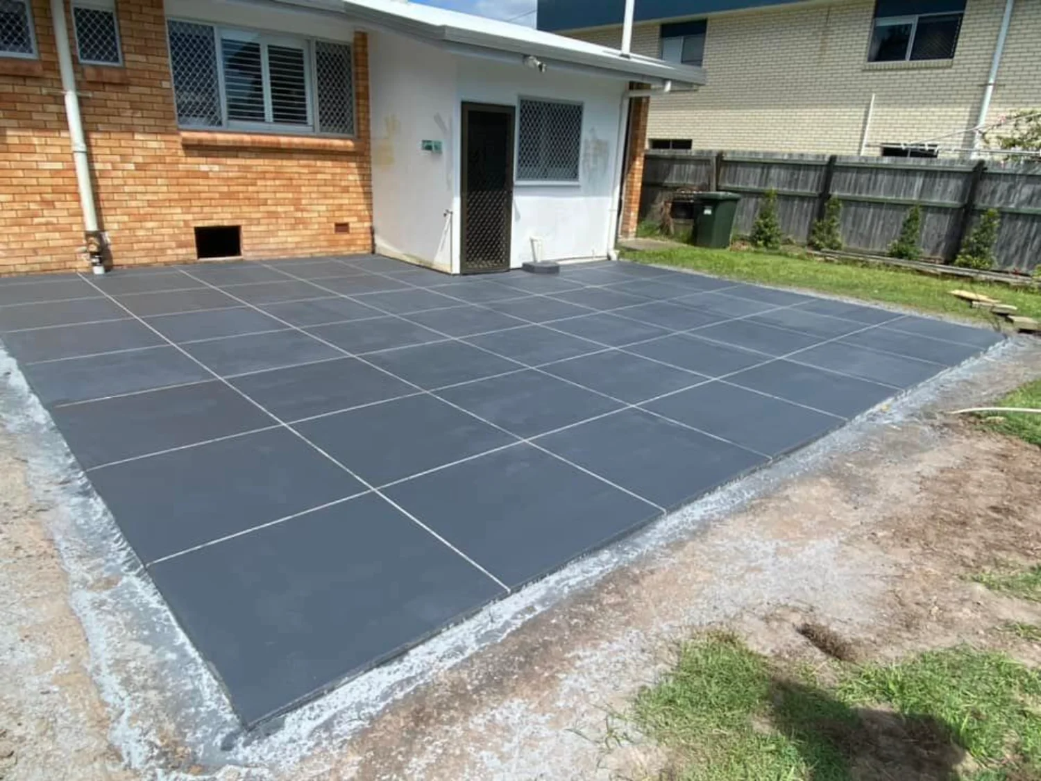 Dark grey stencilled concrete patio with tile pattern by Mark Holstein Concreting in Hervey Bay